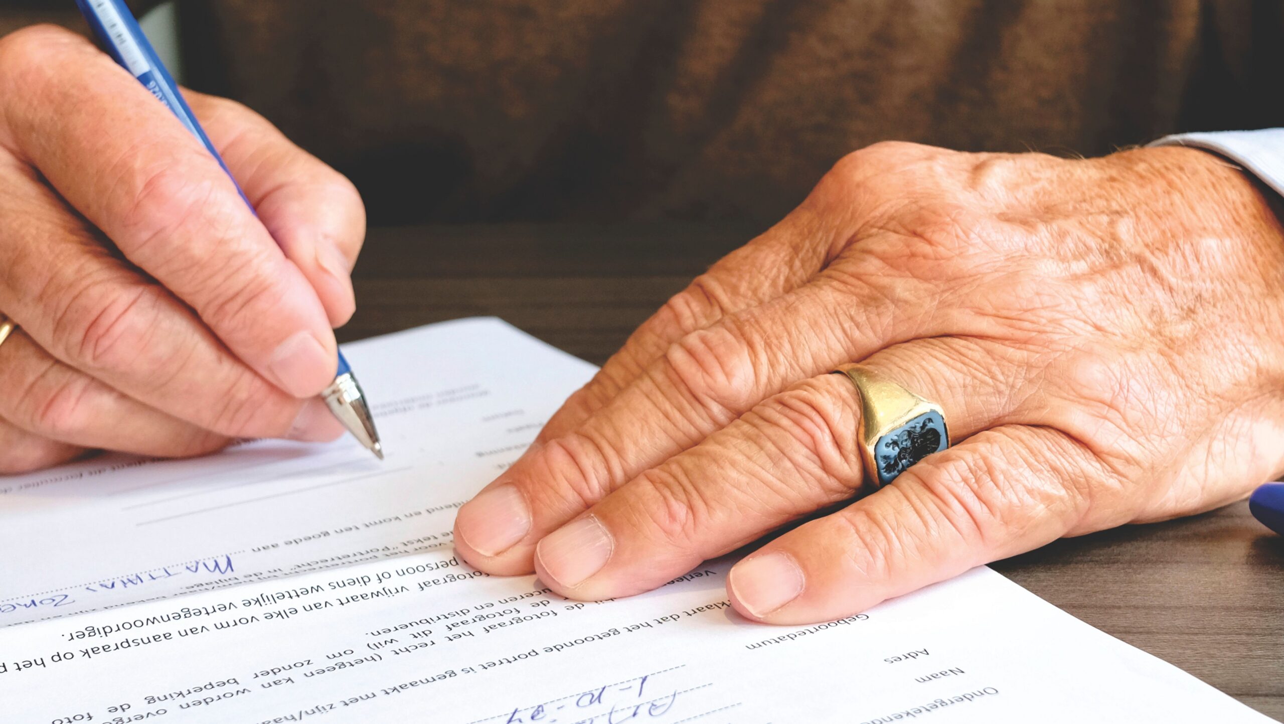 Person signing a paper document with a pen, illustrating estate paperwork for families in Warwick, Rhode Island